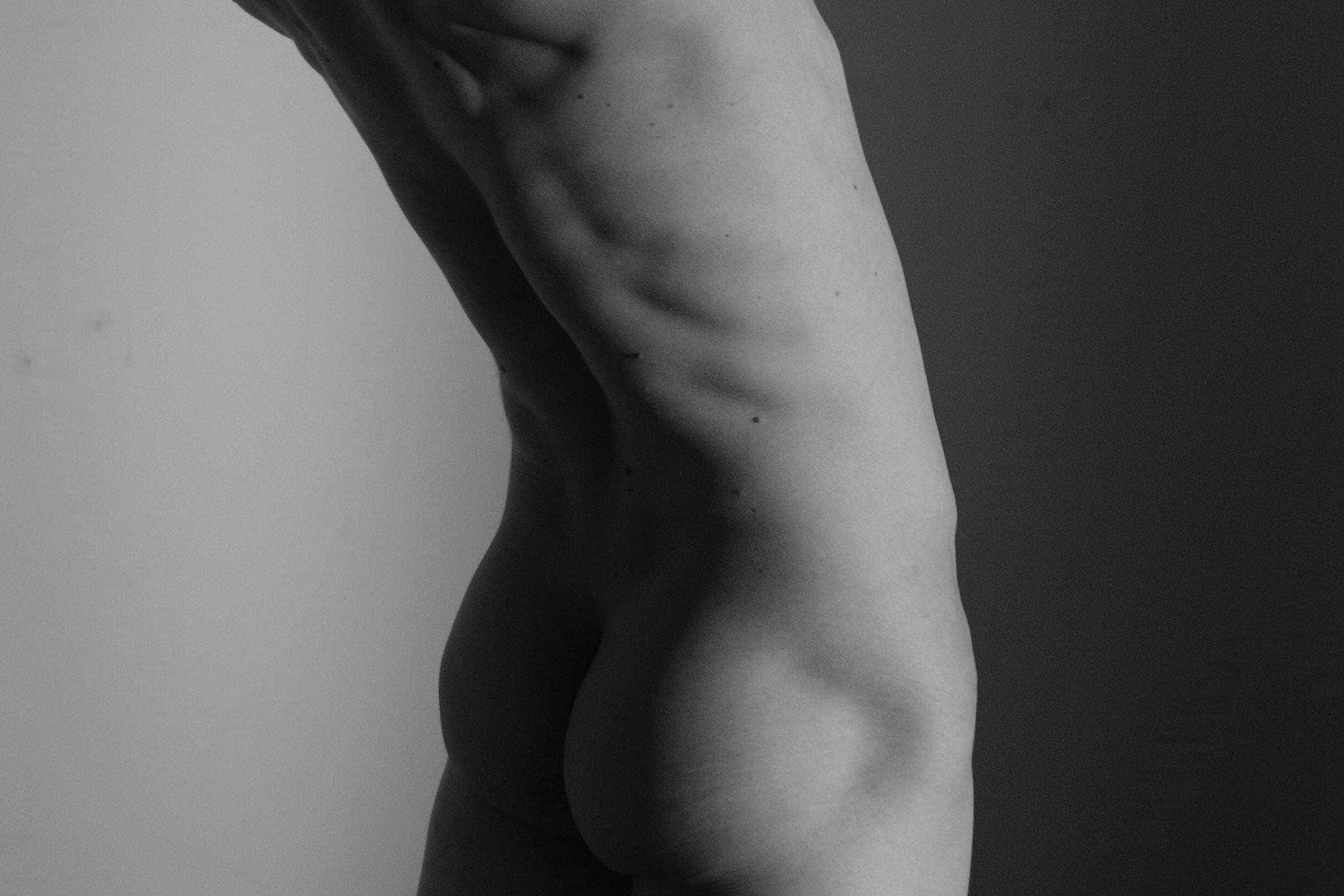 Vue en noir et blanc du dos nu d'un homme maigre avec des muscles et des os visibles.