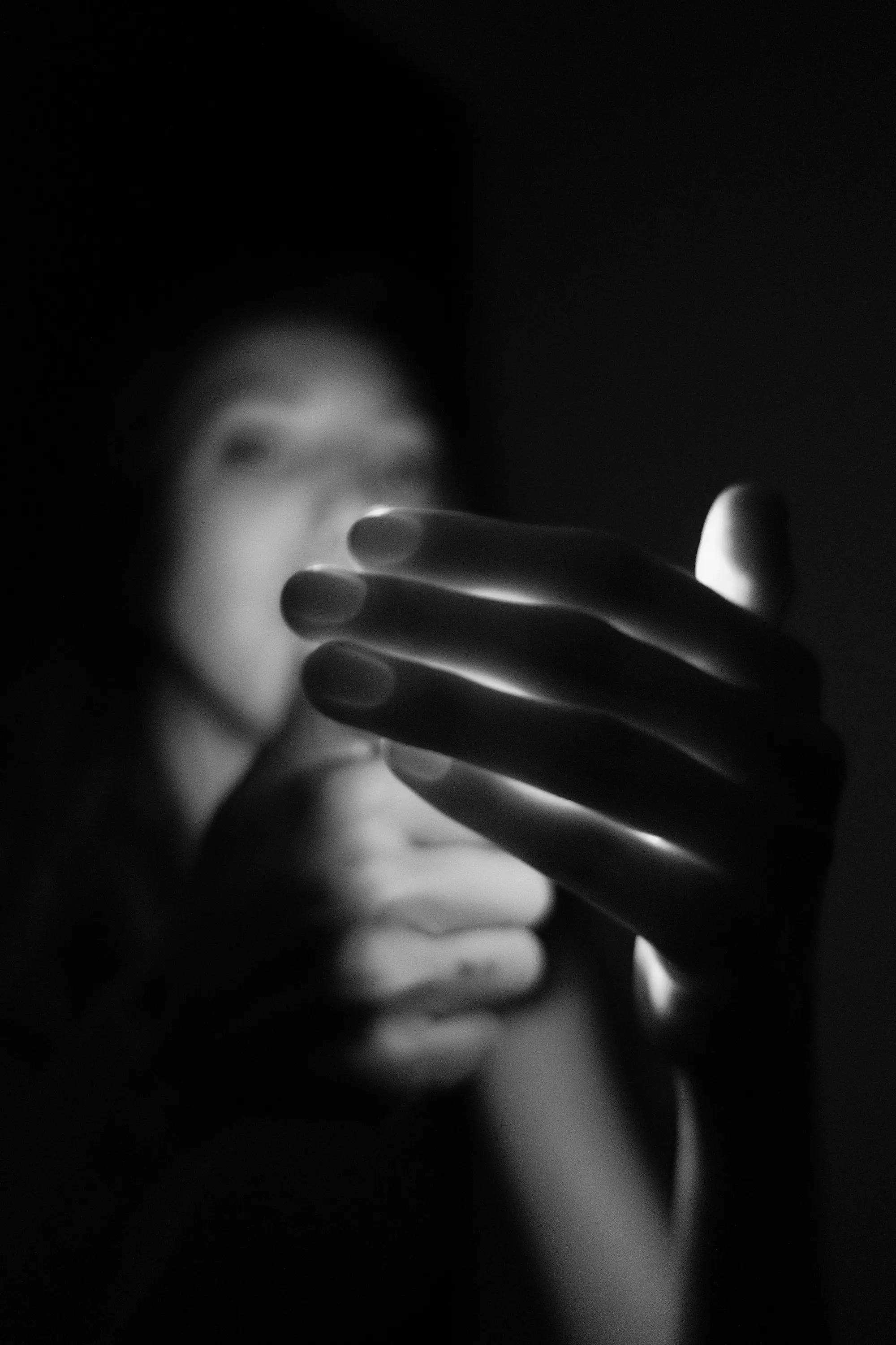 Person tenant une allumette allumée près d'une main dans l'obscurité en lumière douce.