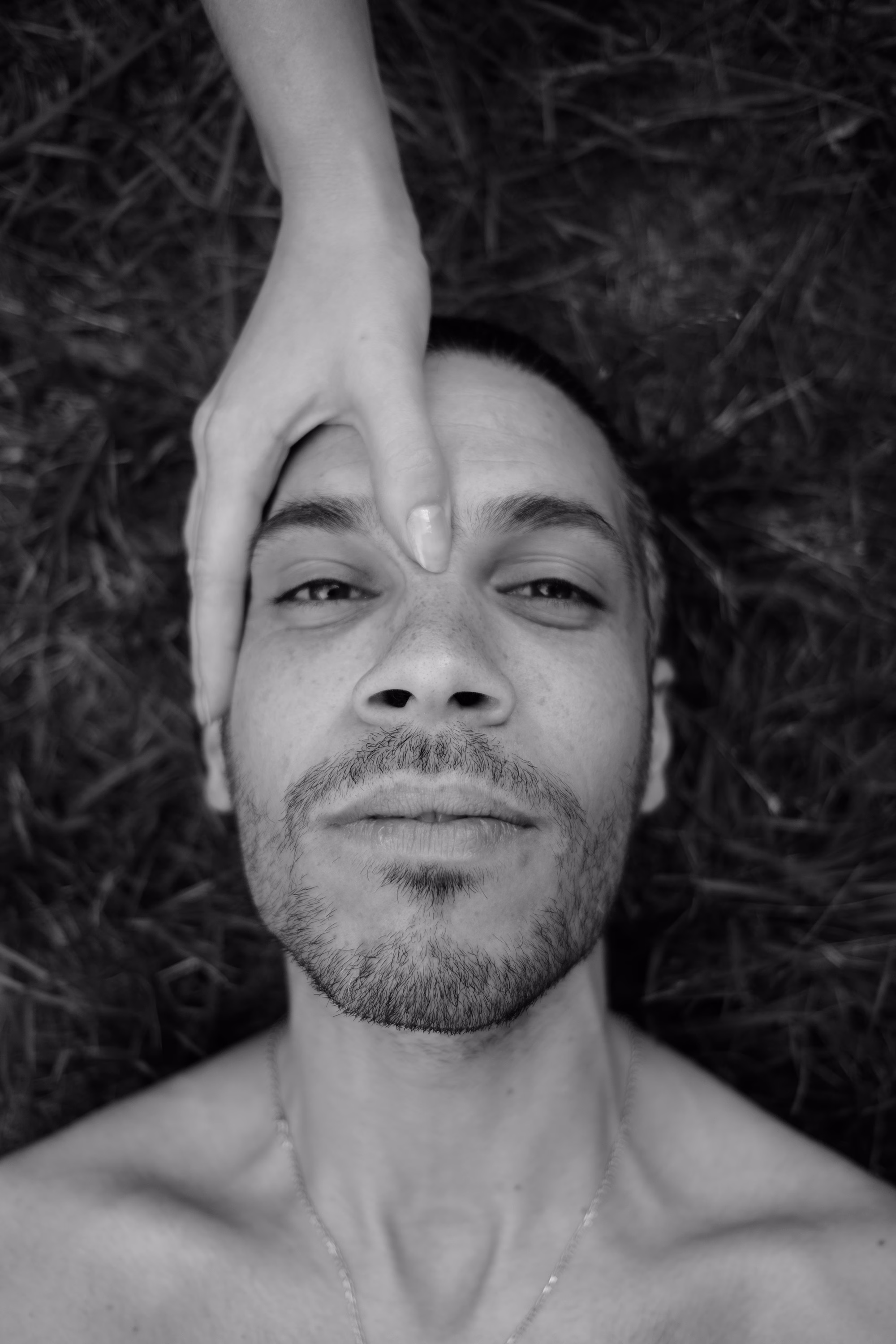 Homme allongé yeux ouverts avec une main posée sur son front, photo en noir et blanc.