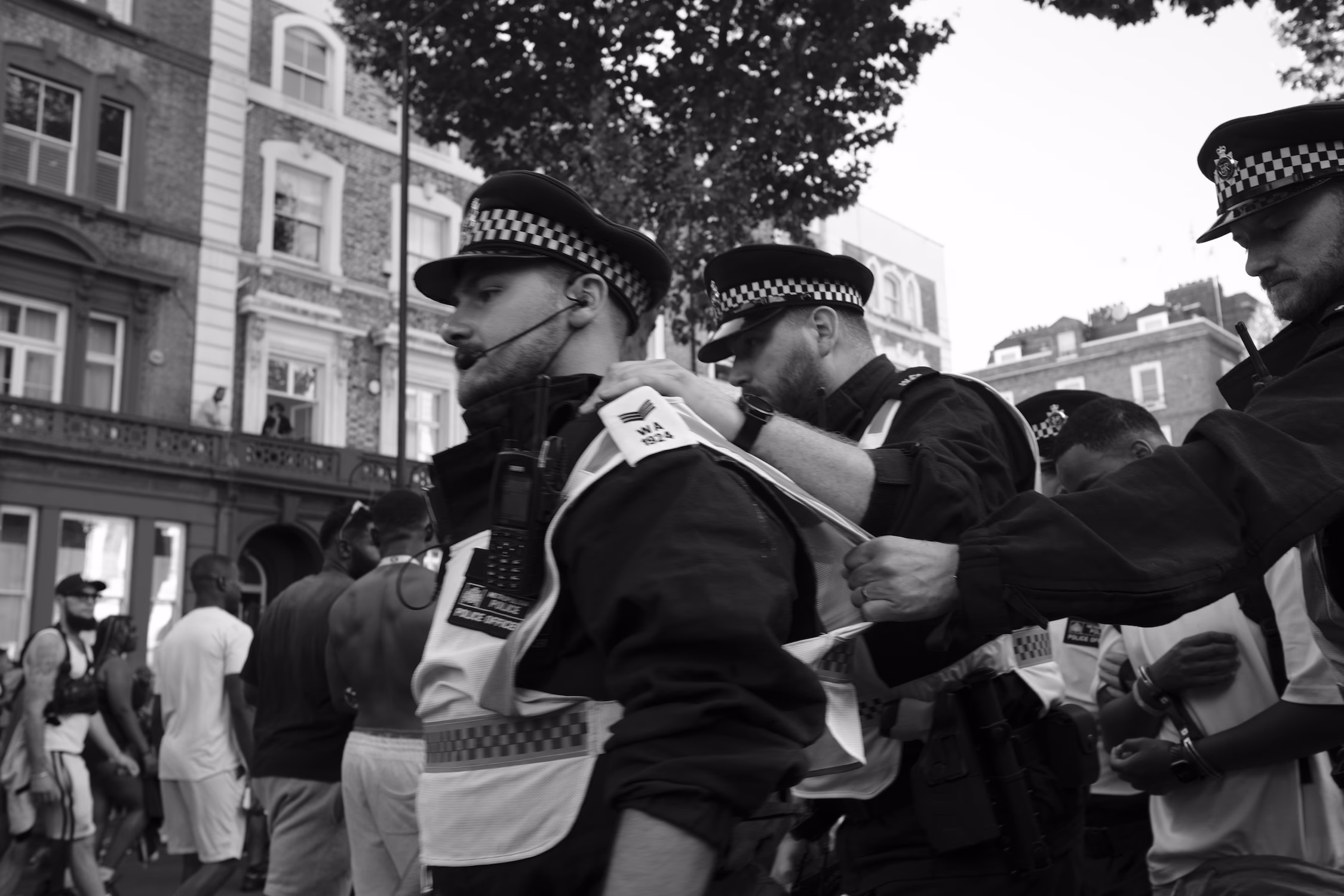 Des policiers menottent plusieurs hommes lors d'un événement urbain animé.
