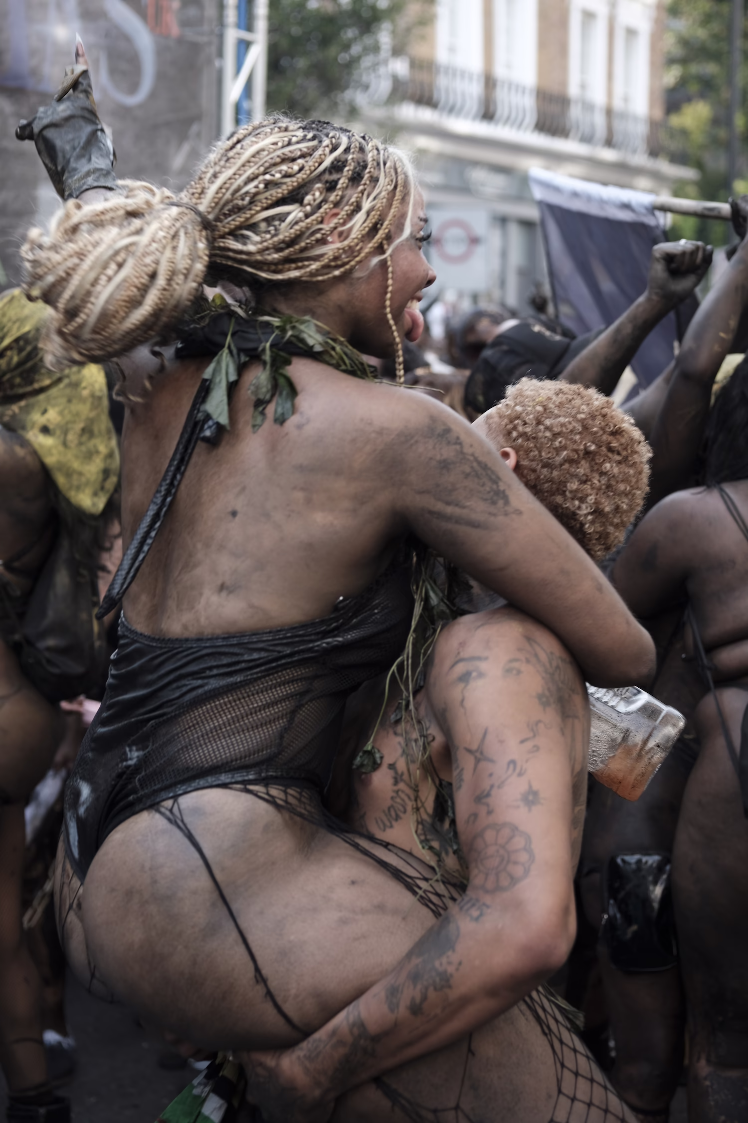 Deux personnes dans une foule, la femme blonde tressée est portée sur les épaules d'un homme tatoué.