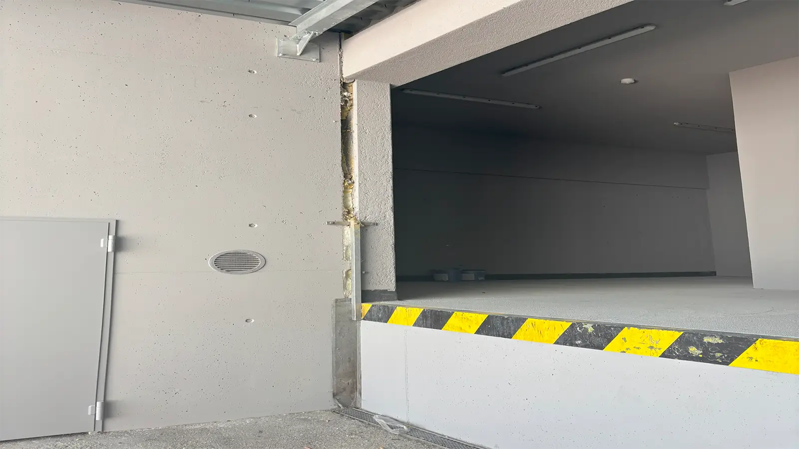 Anlieferungsbereich des Supermarkts. Die Wände und der Boden wurden frisch verputzt und weiß gestrichen.