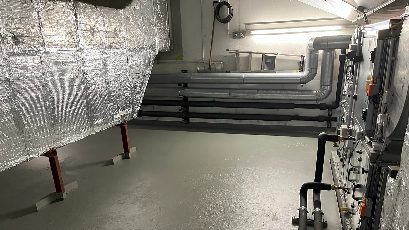 Einer der Technikräume nach der Sanierung. Der Boden wurde neu gemacht, es sind teilweise neue technische Geräte, Belüftungsanlagen und Gebäudetechnik zu sehen. 