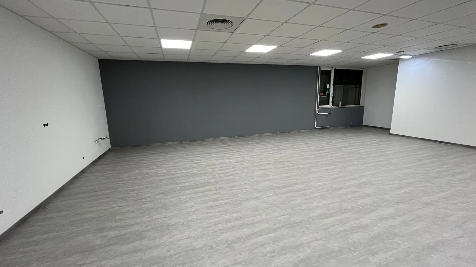 Einer der Aufenthaltsräume nach der Sanierung. Der Boden und die Wände wurden erneuert, die Rückwand ist grau gestrichen.