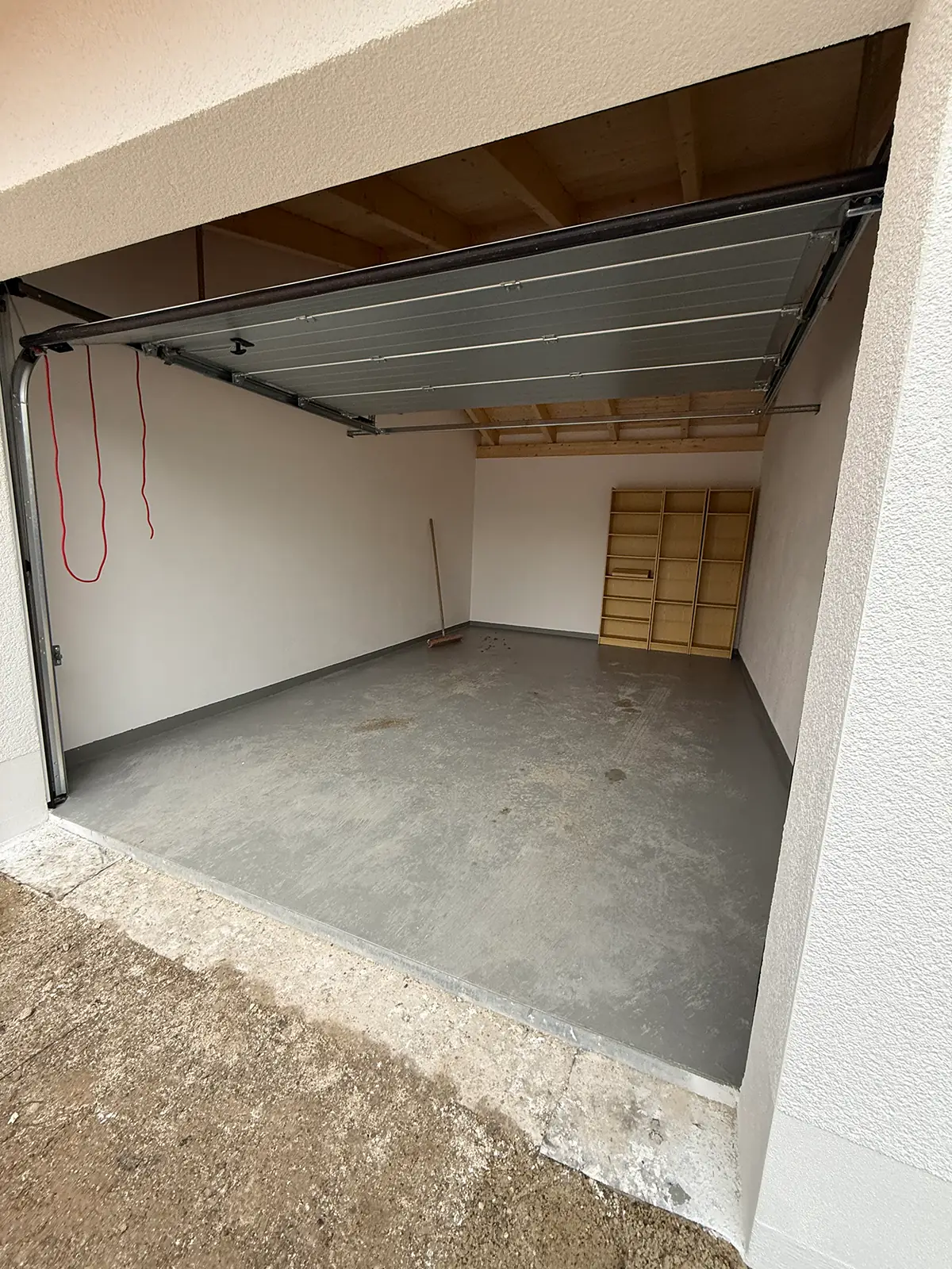 Innenansicht der sanierten Garage. Alle Brandspuren und -schäden wurden beseitigt. Im Hintergrund ist ein Besen und ein Holzregal zu sehen.