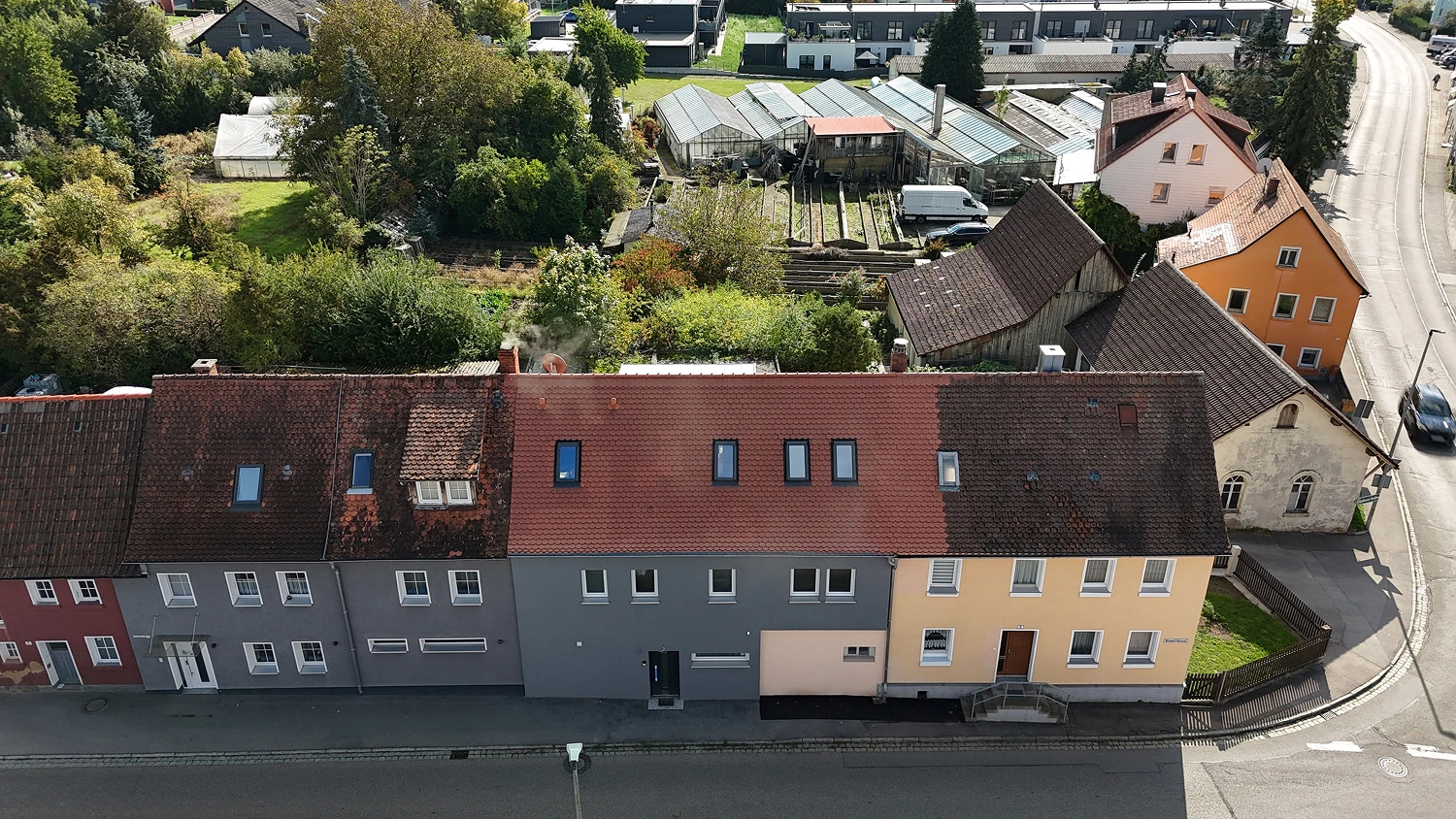 Reihenhauszeile mit brandsaniertem Wohnhaus aus der Vogelperspektive