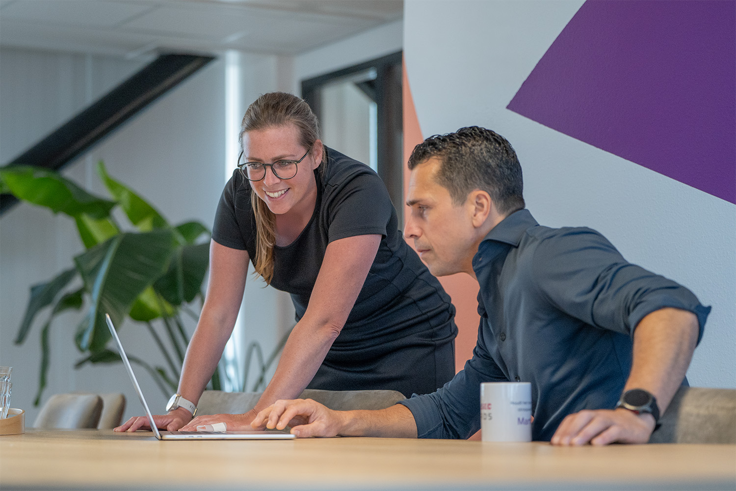 Roos and Charl, founders of PuraSec, smile at a laptop in the office.