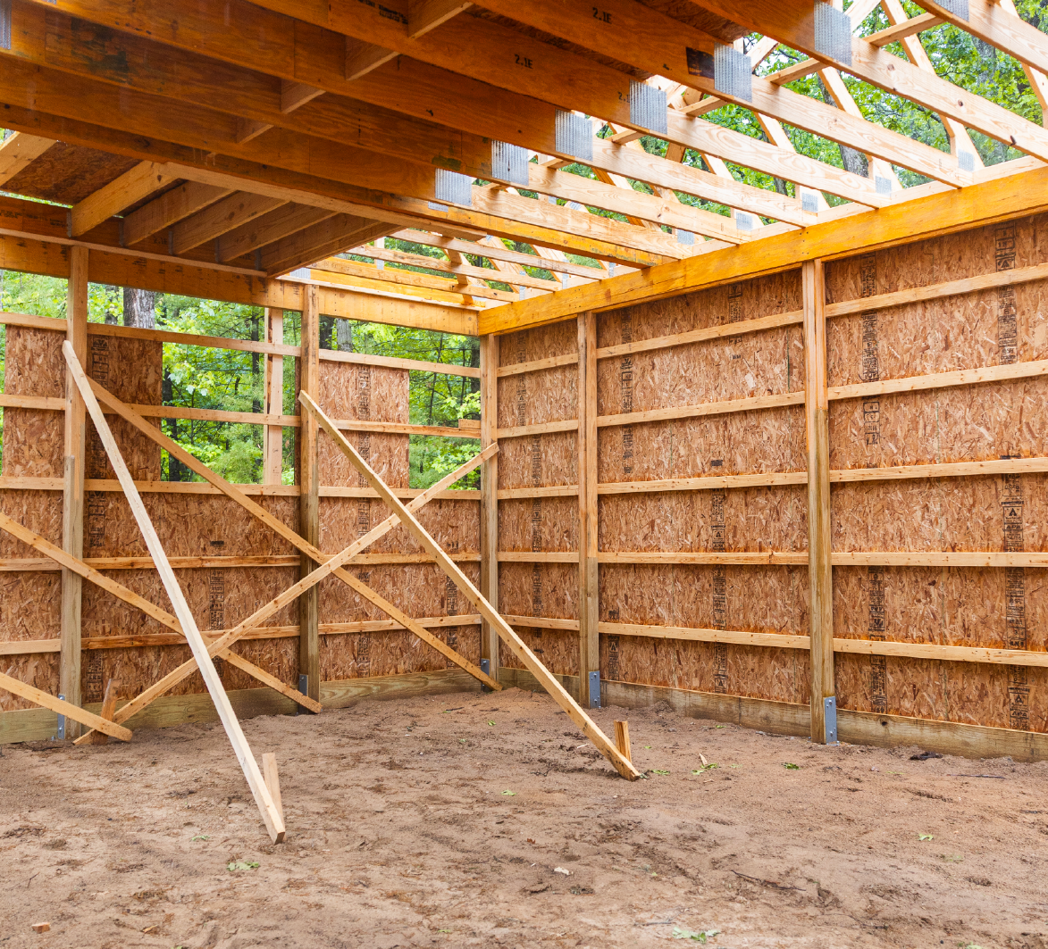Interior view of a wooden barn structure under construction with exposed framing and plywood walls.