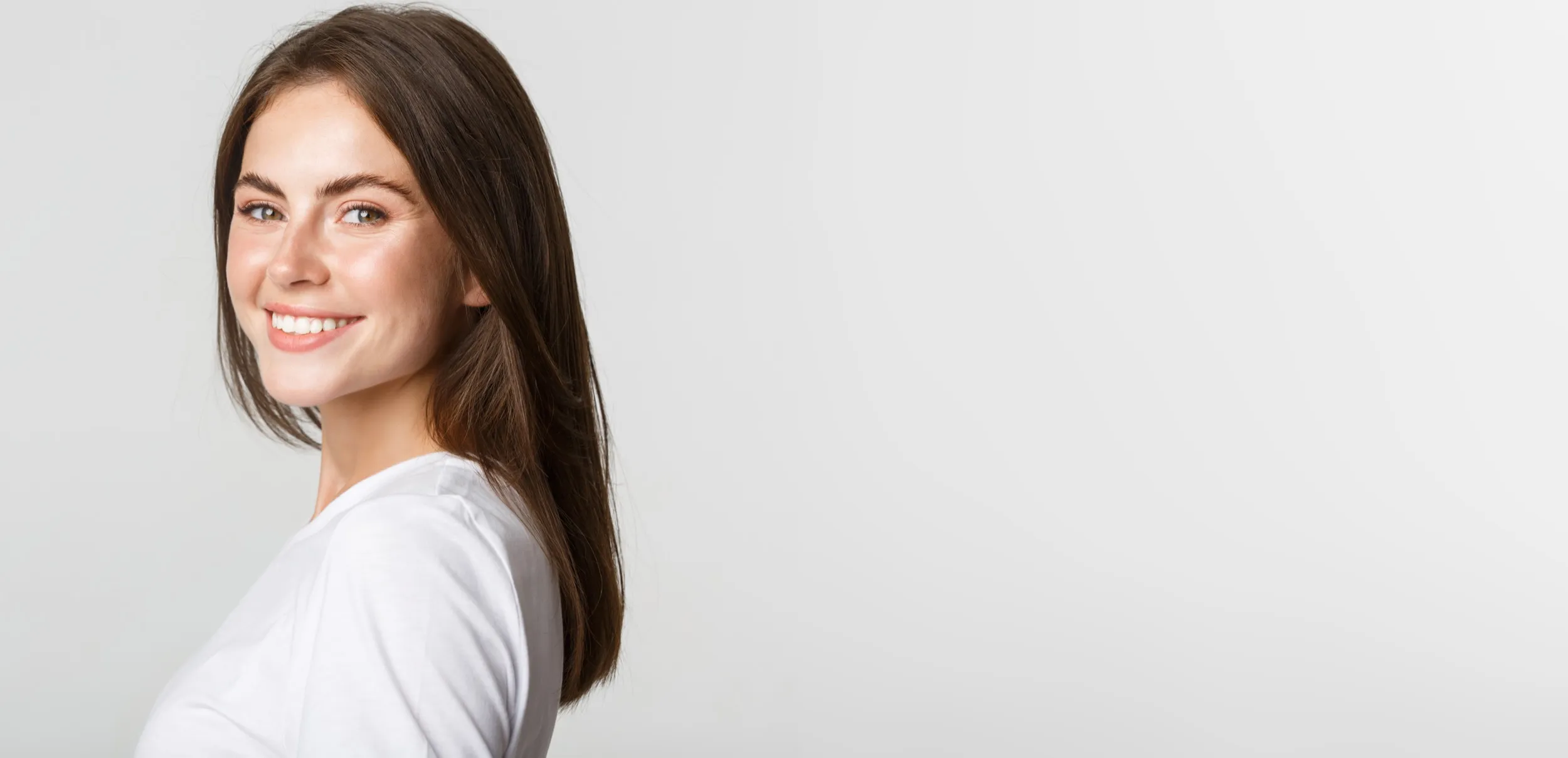 Smiling woman with long brown hair in white shirt against white background