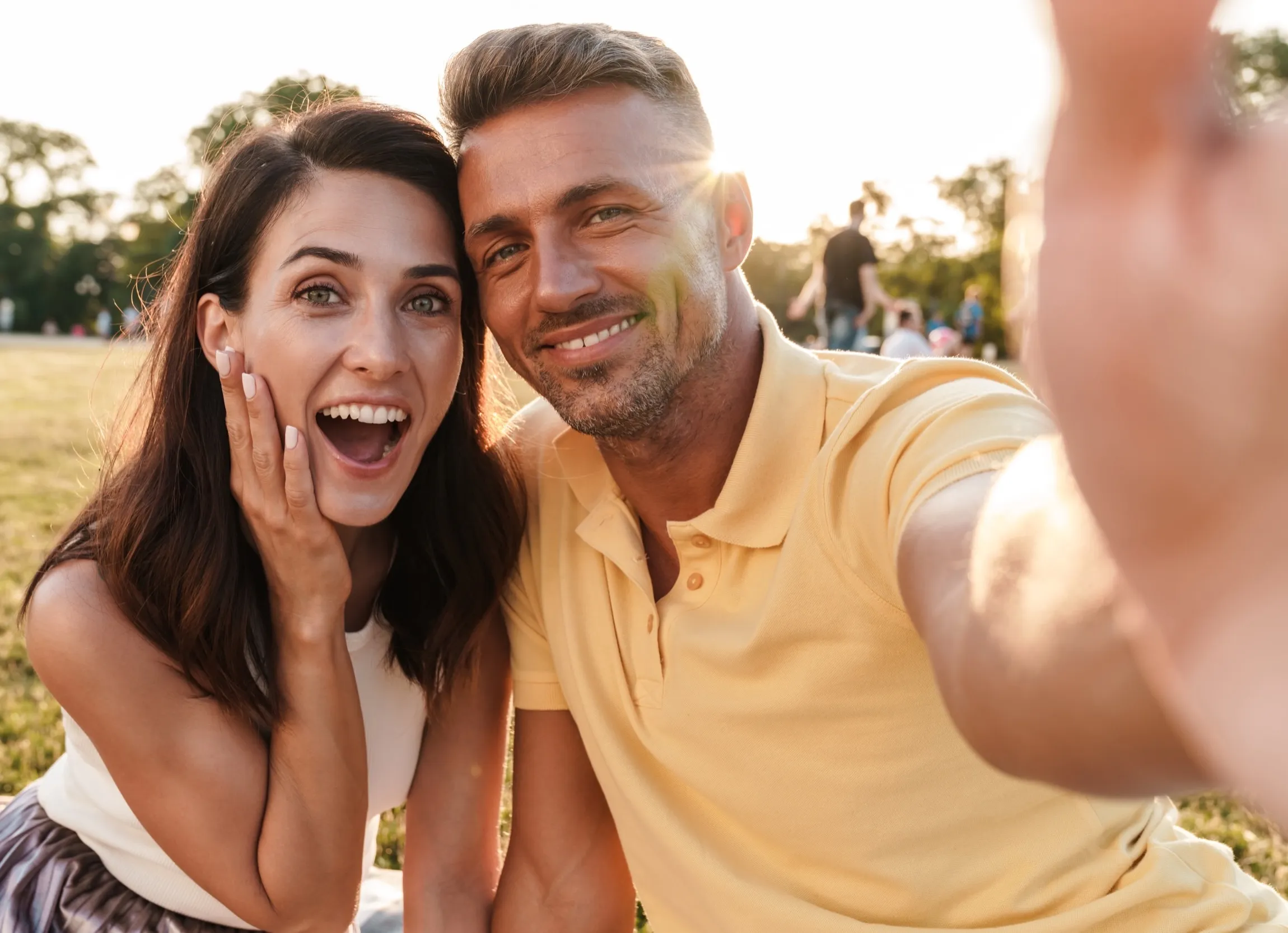Joyful couple taking a selfie together outdoors on a sunny day