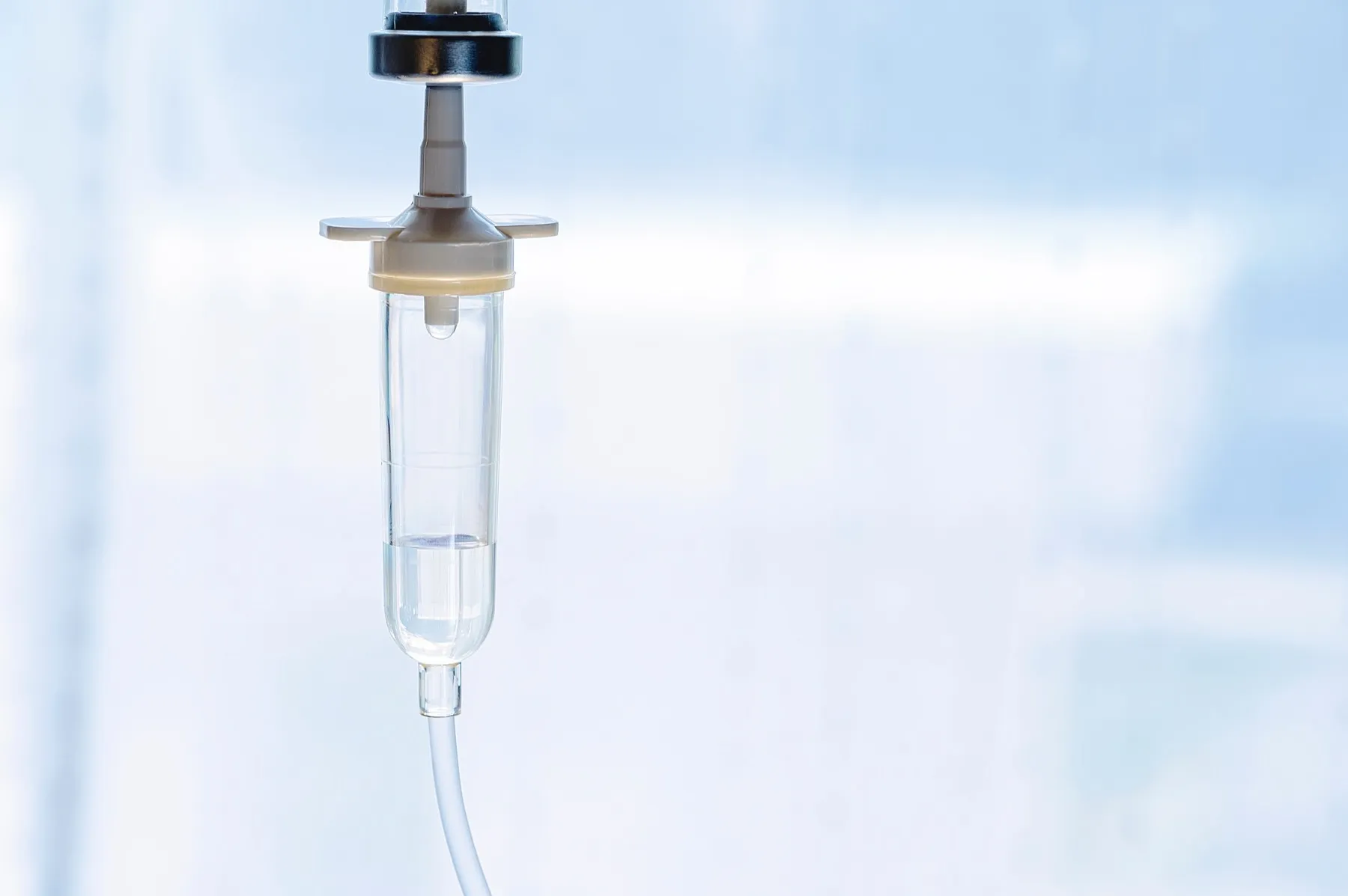 Medical IV drip bag with fluid hanging on a clear background