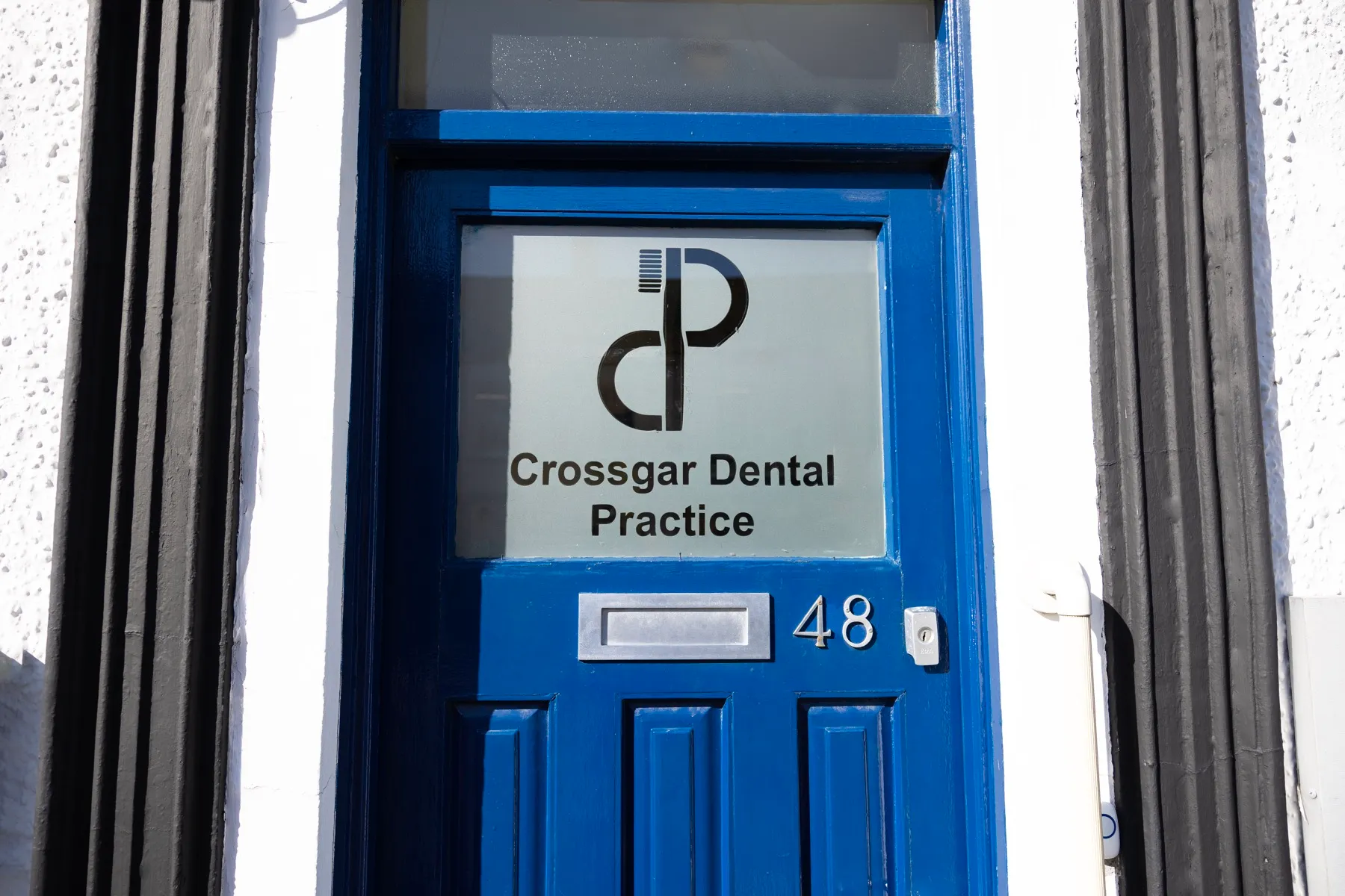 Blue door entrance to Crossgar Dental Practice at number 48
