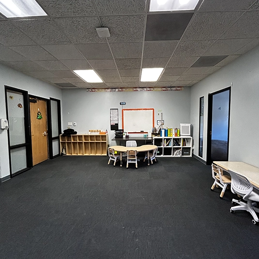Open therapy room overview with workstations and cubbies
Open therapy room with workstations, kidney tables, and organized learning materials at our San Diego clinic.