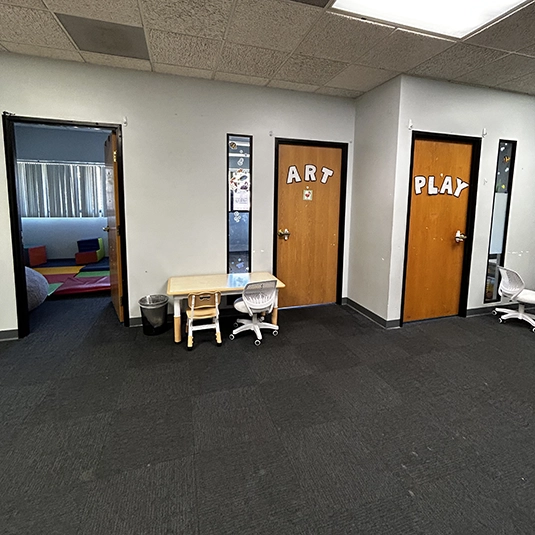 Hallway with Art and Play room doors and child workstation
Hallway connecting the Art and Play rooms with a child workstation at the Alongside San Diego ABA clinic.