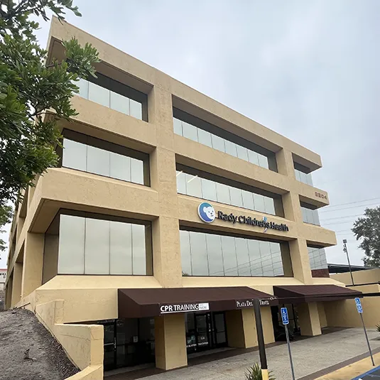 Exterior of the Oceanside clinic, a four-story tan medical building with Rady Children's Health signage and ground-level awnings.