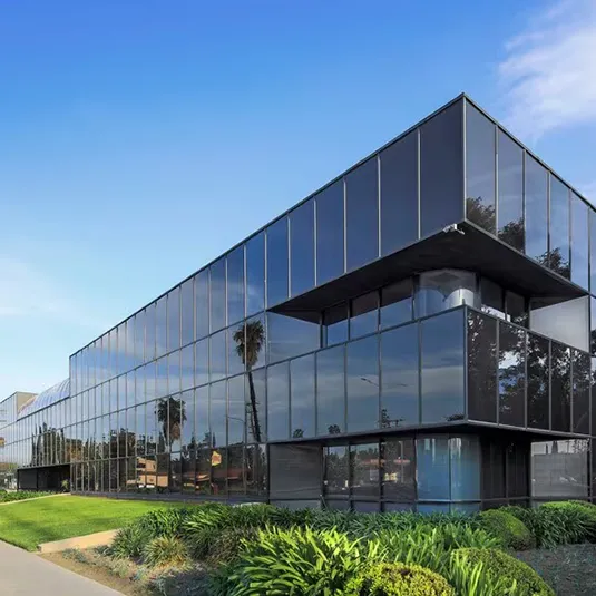 Exterior of the Van Nuys clinic building, a modern multi-story glass office building with landscaped greenery under a clear blue sky.