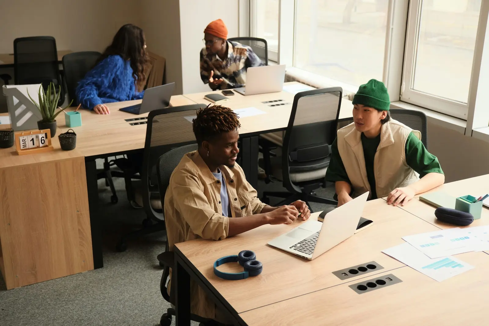 Small business team collaborating at laptops with printed documents on the desk, illustrating how teams manage mail-driven workflows