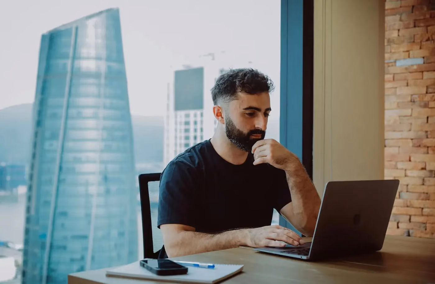 Startup founder working on a laptop in a transitional space, representing the challenge of using a personal address for a growing business