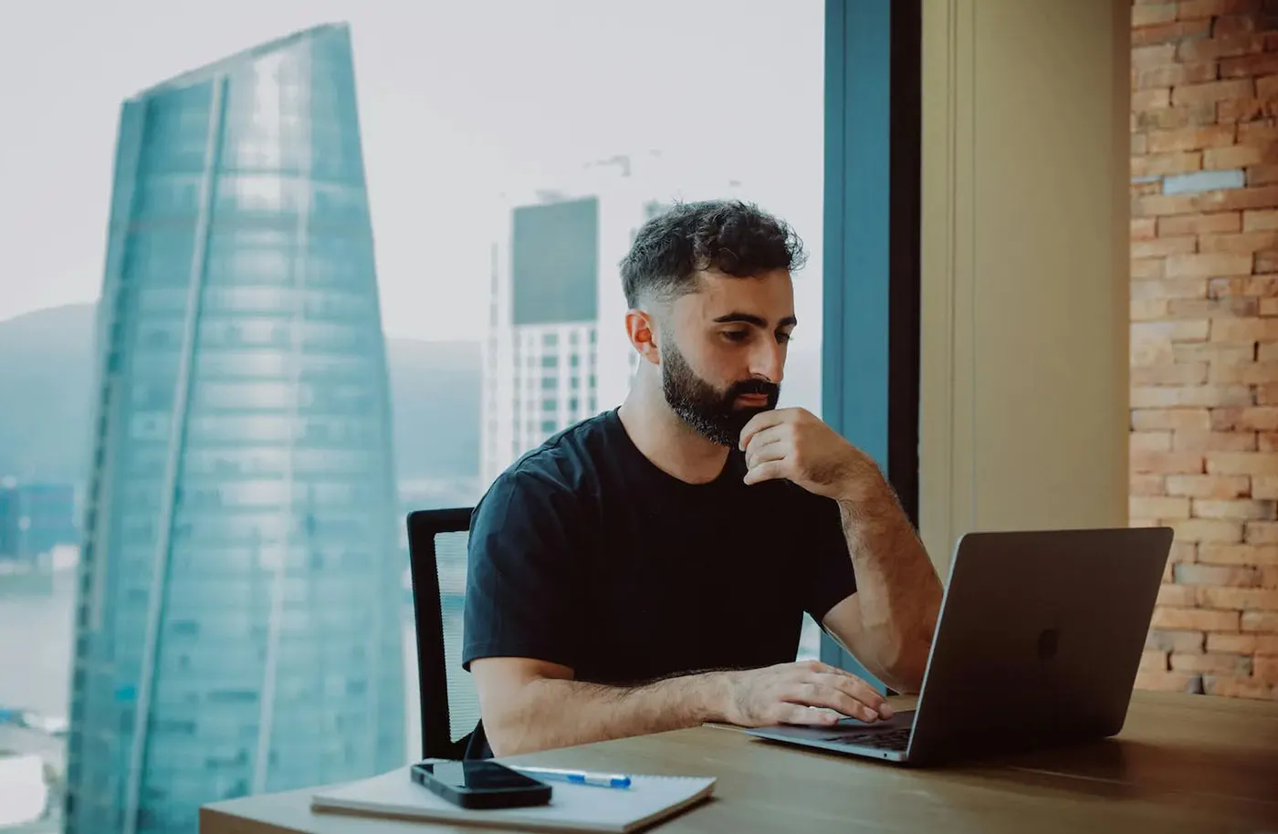 Startup founder working on a laptop in a transitional space, representing the challenge of using a personal address for a growing business