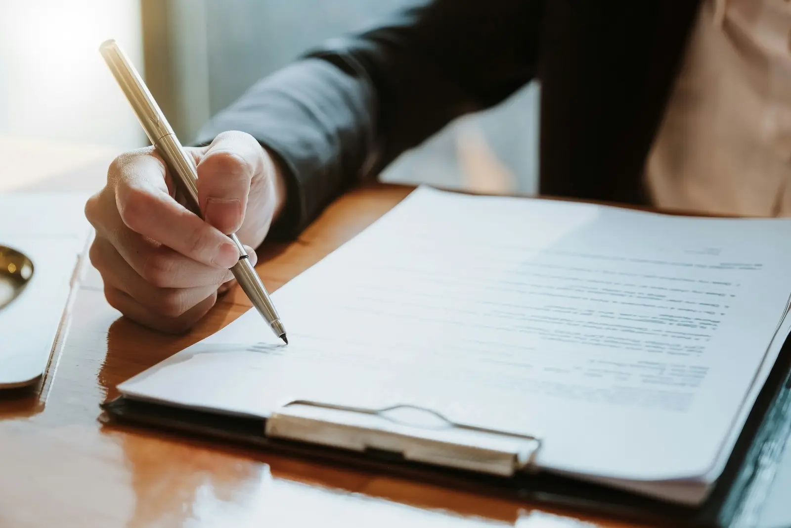 Business owner signing legal document on clipboard, responding to legal mail on time prevents default judgments and compliance violations