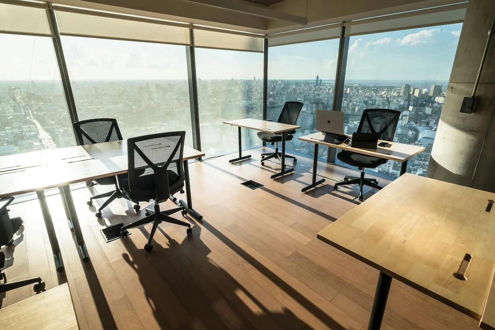 Empty office with vacant desks and floor-to-ceiling city views, representing a business closing its office and managing mail forwarding