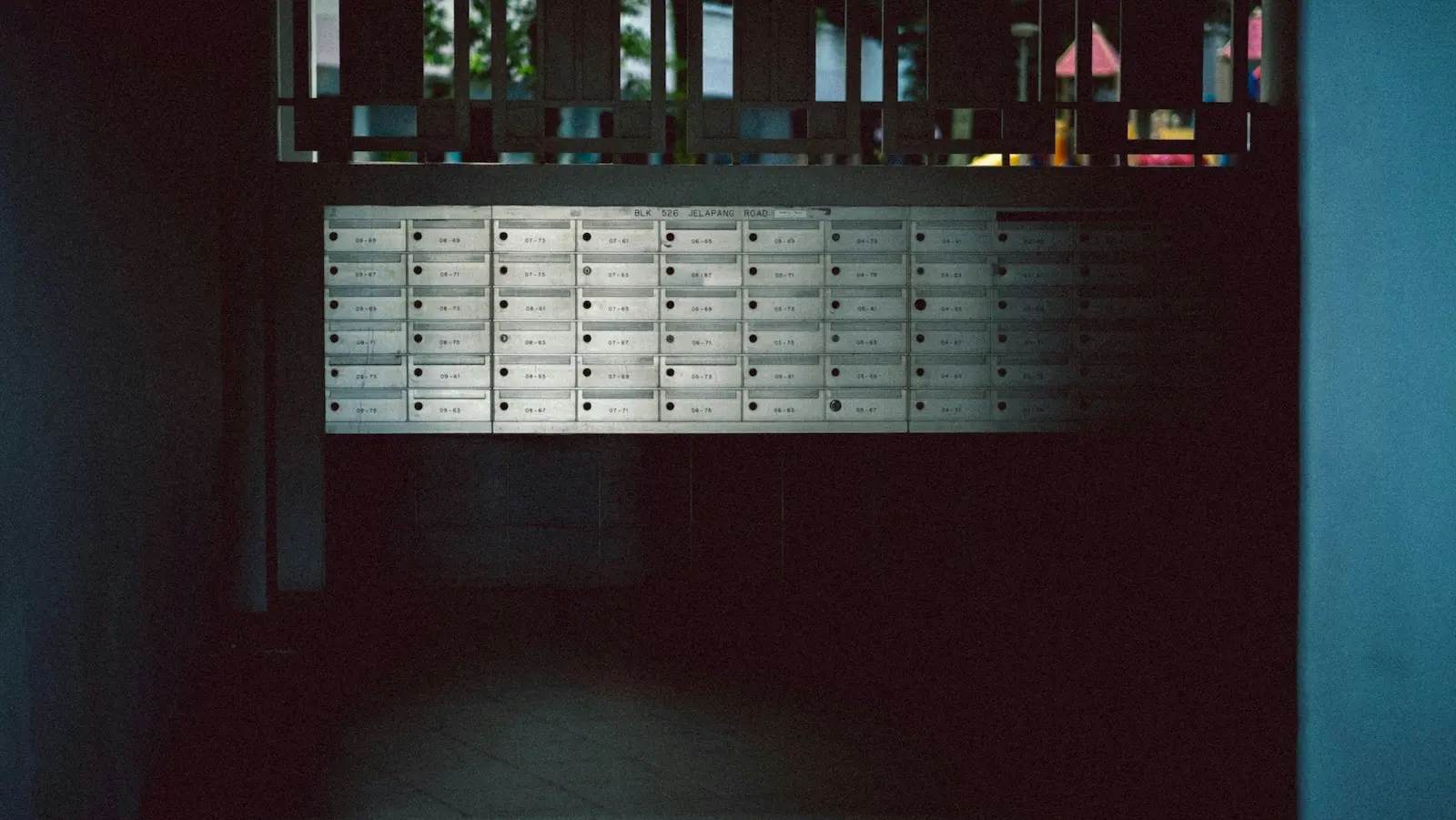 Wall of numbered mailboxes in a dim apartment corridor, representing the traditional mailroom setup businesses are replacing with mail forwarding services