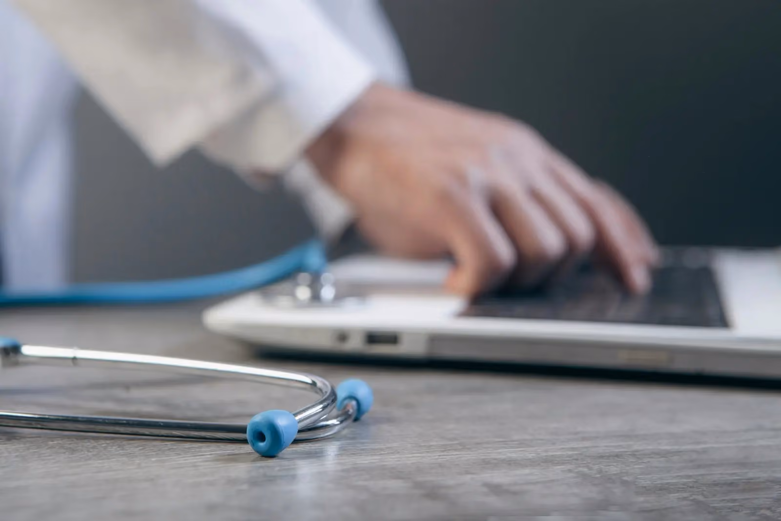 Stethoscope beside a laptop as a clinician manages mail digitally in a medical office