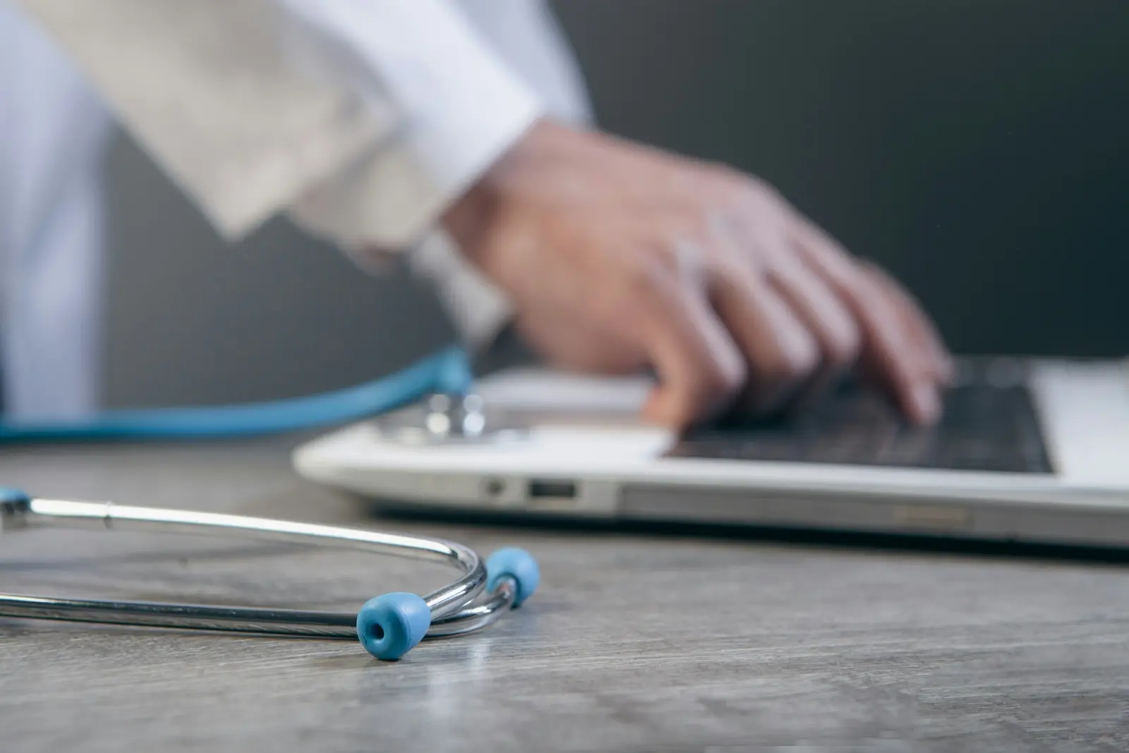 Stethoscope beside a laptop as a clinician manages mail digitally in a medical office