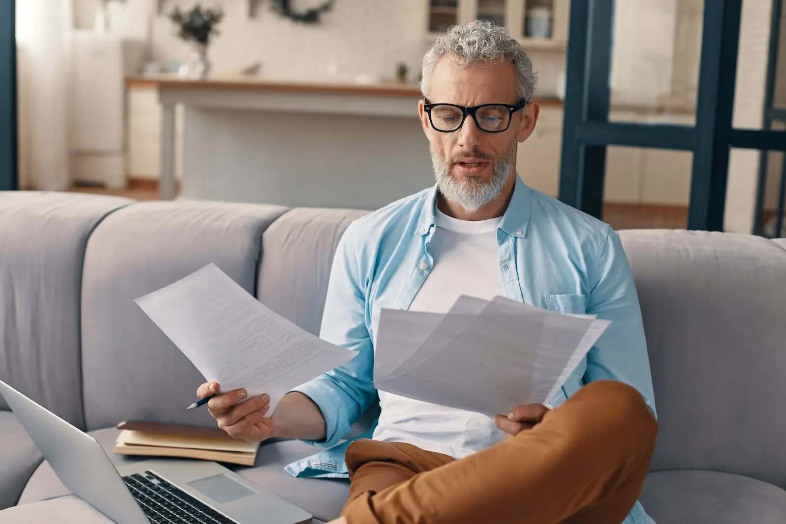Small business owner reviewing business checks and paperwork while working remotely with a laptop before making a remote check deposit.