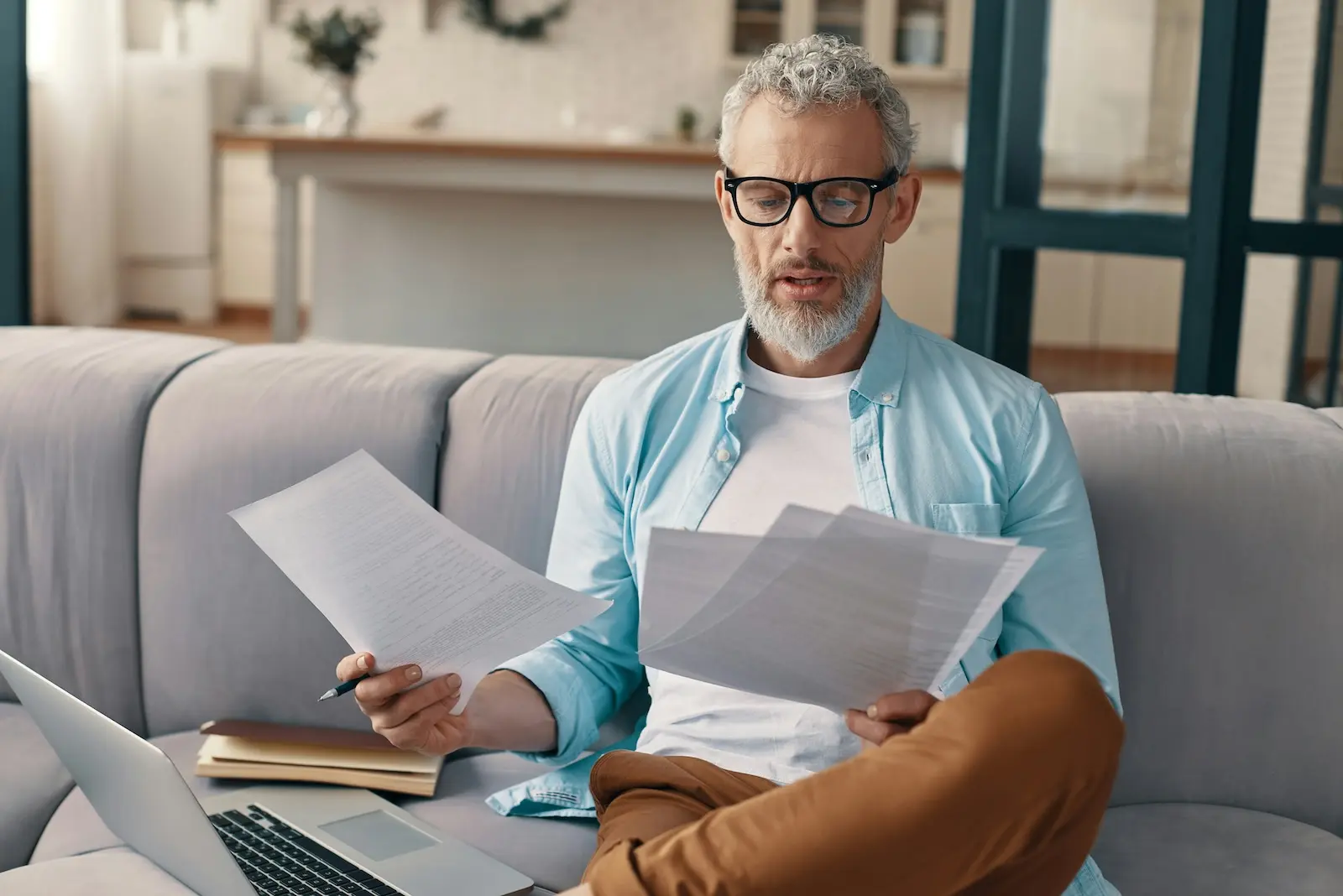 Small business owner reviewing business checks and paperwork while working remotely with a laptop before making a remote check deposit.