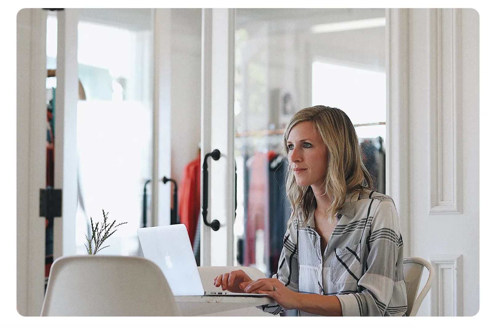 Small business owner managing her virtual mailbox on a laptop in her storefront — comparing iPostal1 alternatives
