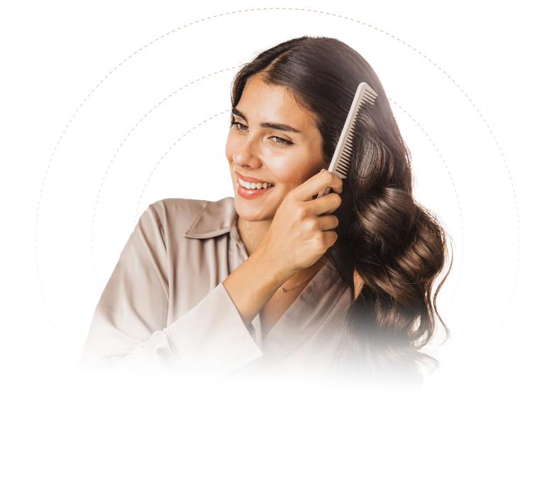 Smiling woman with long, wavy dark hair combing her hair with a beige comb.
