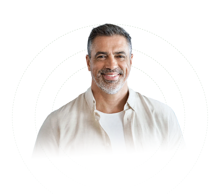 Smiling middle-aged man with salt-and-pepper hair and beard wearing a light beige open shirt over a white t-shirt.
