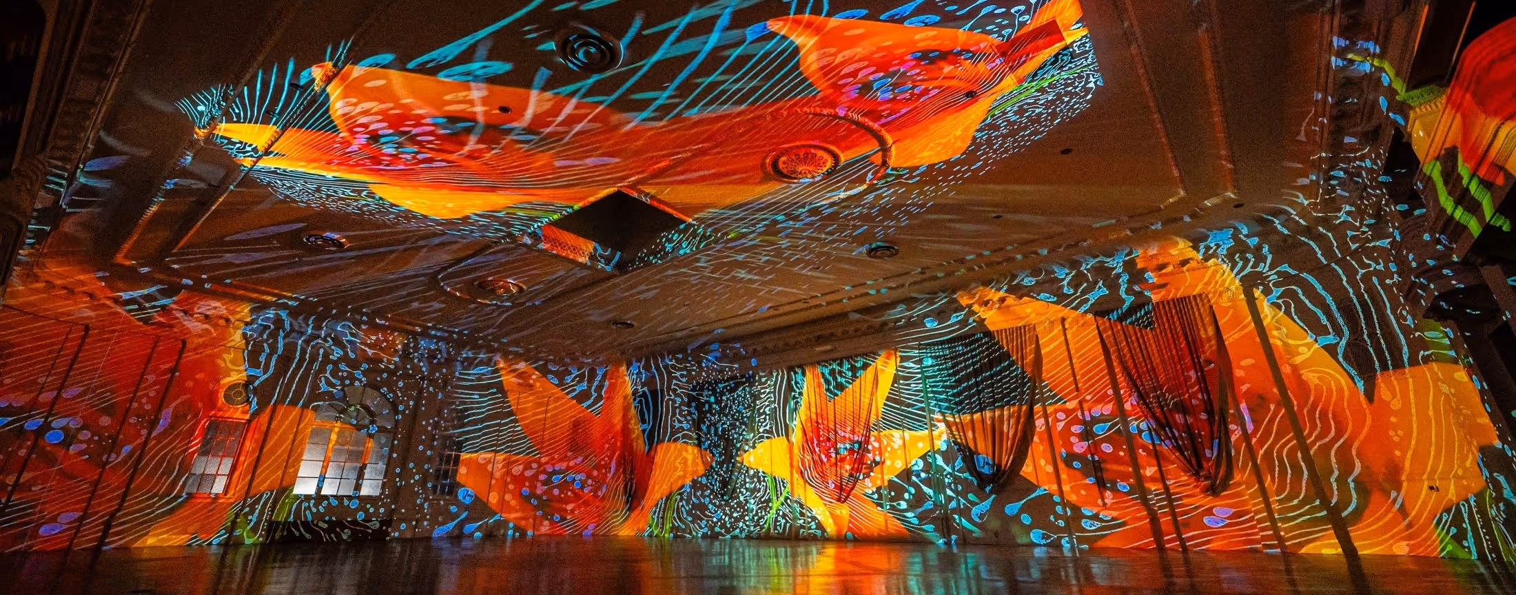 A striking venue photo showing modern projection mapping techniques applied to the ballroom.