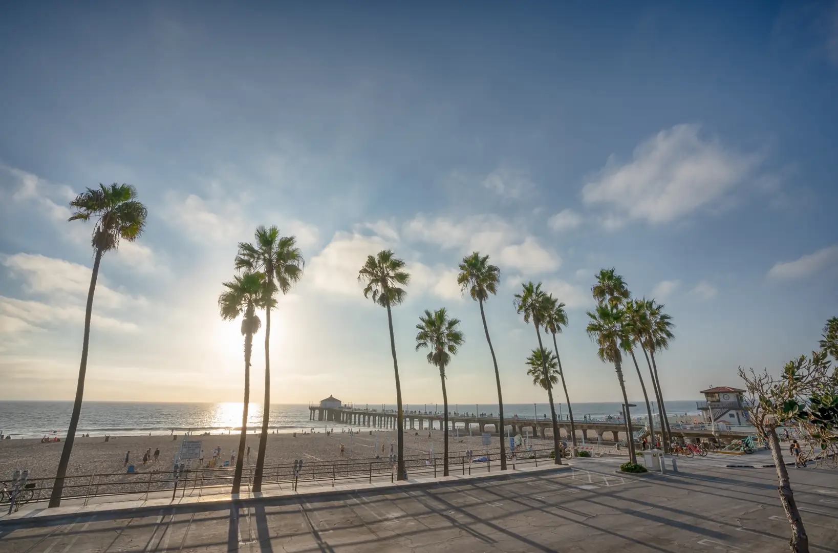 Palm trees and the Manhattan Beach Pier with the sun low over the ocean