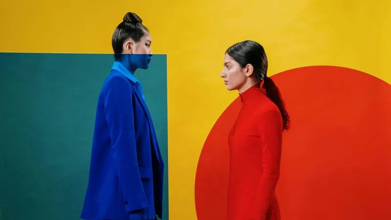 Thumbnile image of our work. In this image "Two women dressed in vibrant colors standing side by side, showcasing a lively and cheerful atmosphere."