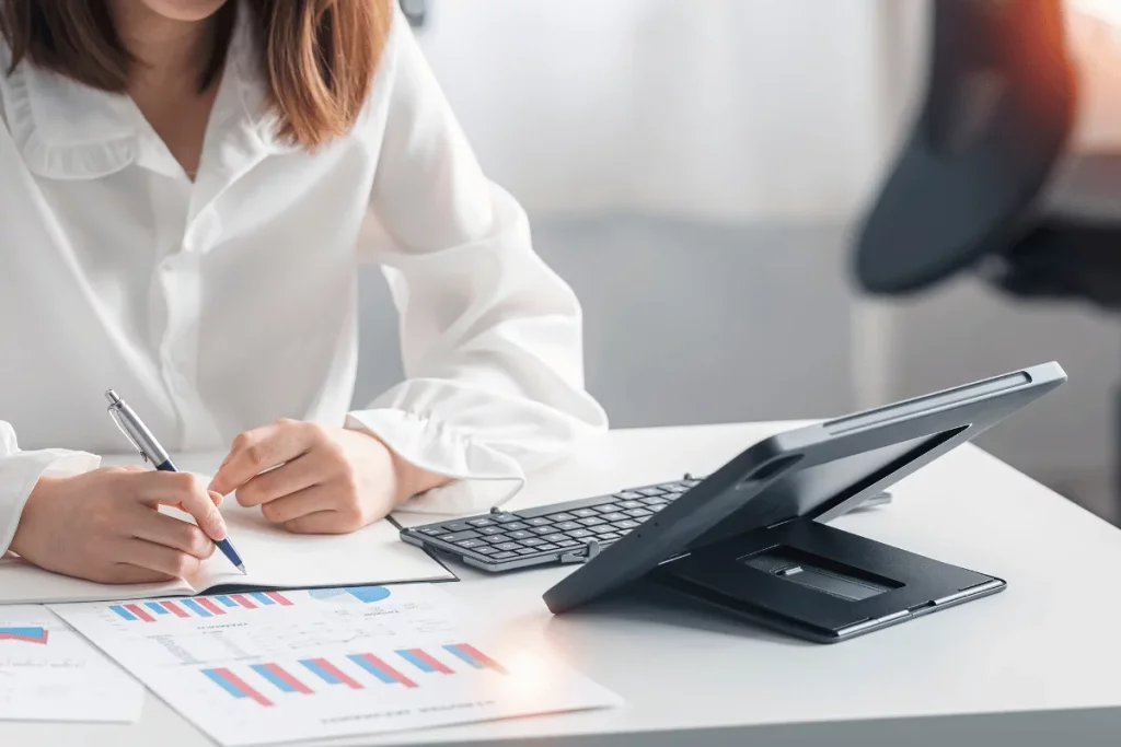 Detailed view of a professional's hands working on financial charts, symbolizing focus and analytical thinking.