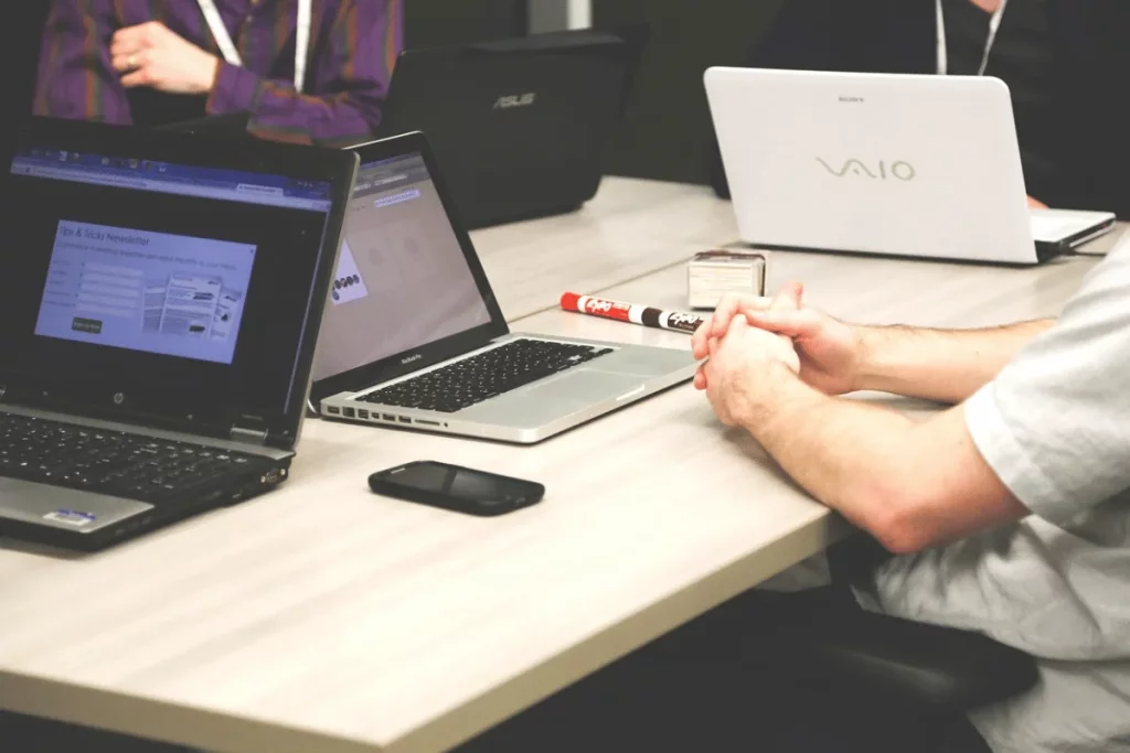 Professional setting with attendees using laptops and a detailed view of joined hands.
