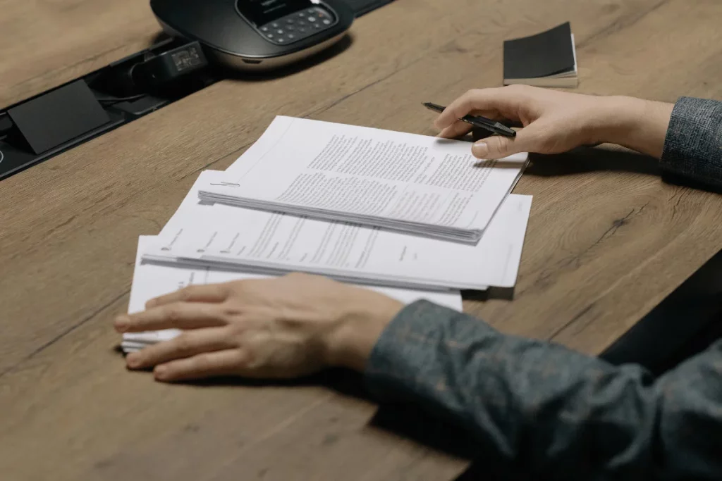 Person reviewing and sorting documents on a desk, with a telephone in the background.