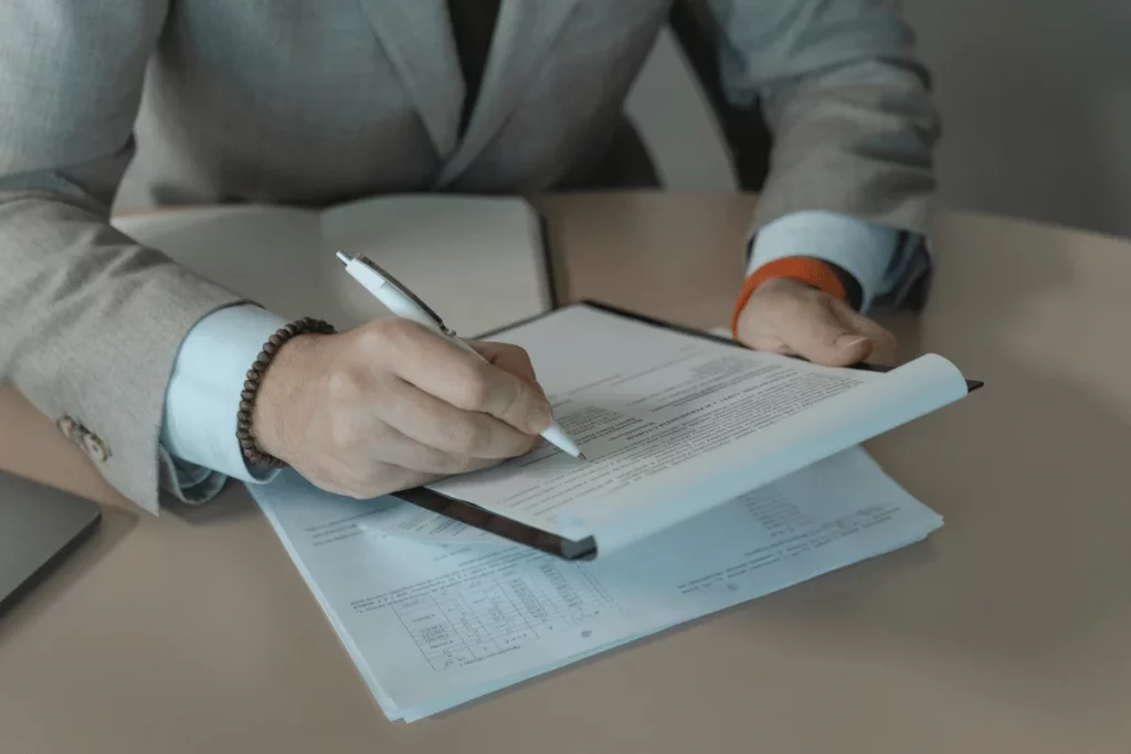 Business professional signing a document at a desk.