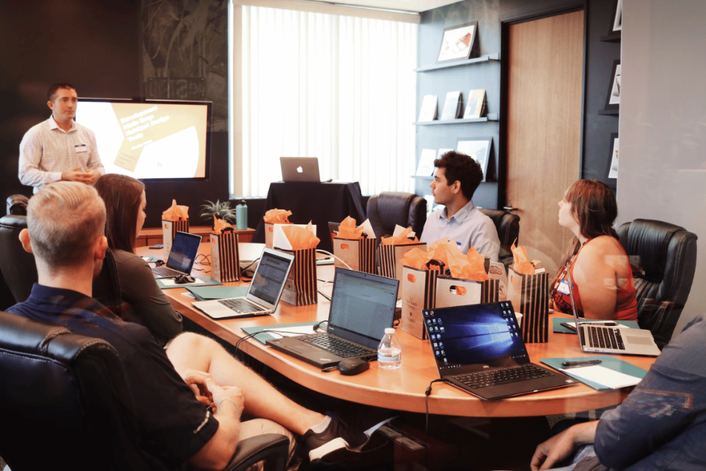 A group of people sitting around a table with laptops.