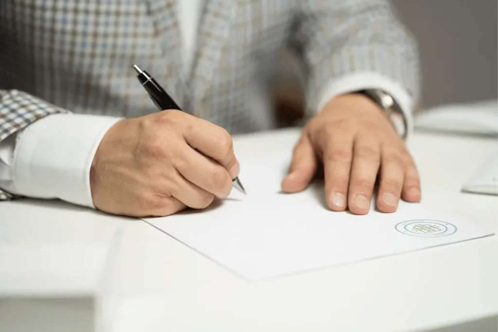 Close-up of a person signing a document with a pen.