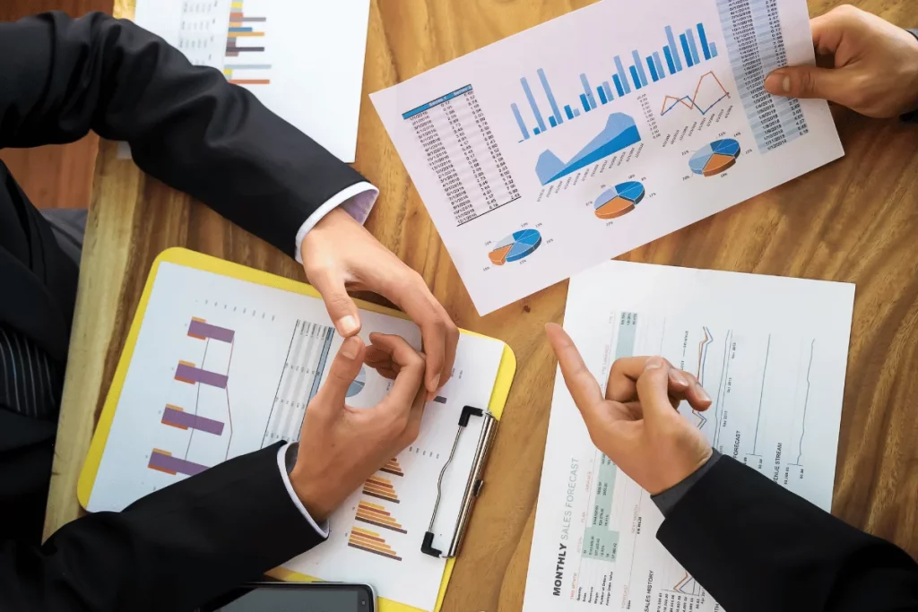 Professionals discuss reports with charts and graphs on a table.