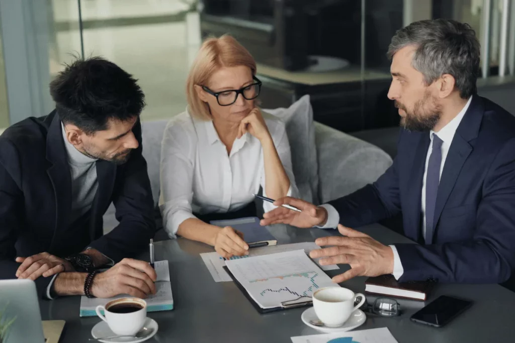 Business team discussing financial charts and data during a meeting in a modern office setting with coffee cups on the table.