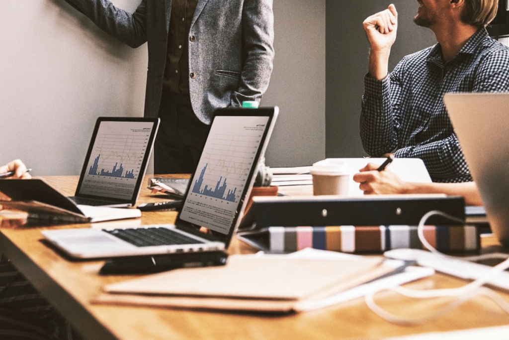 Colleagues in a meeting room with digital tablets displaying charts and a coffee cup visible.