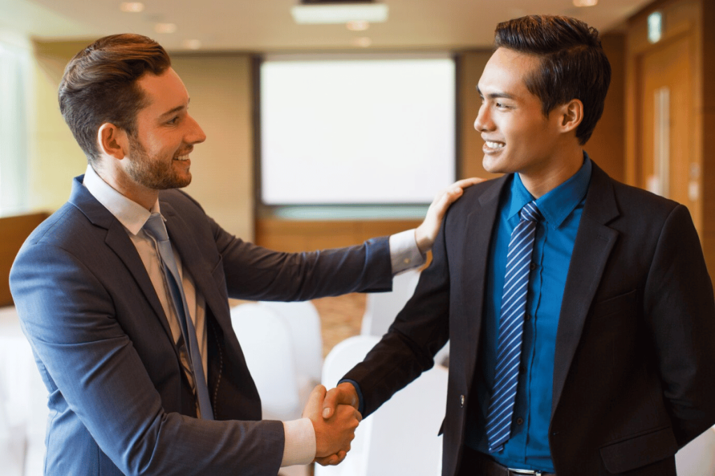 Two individuals shaking hands in a conference room.