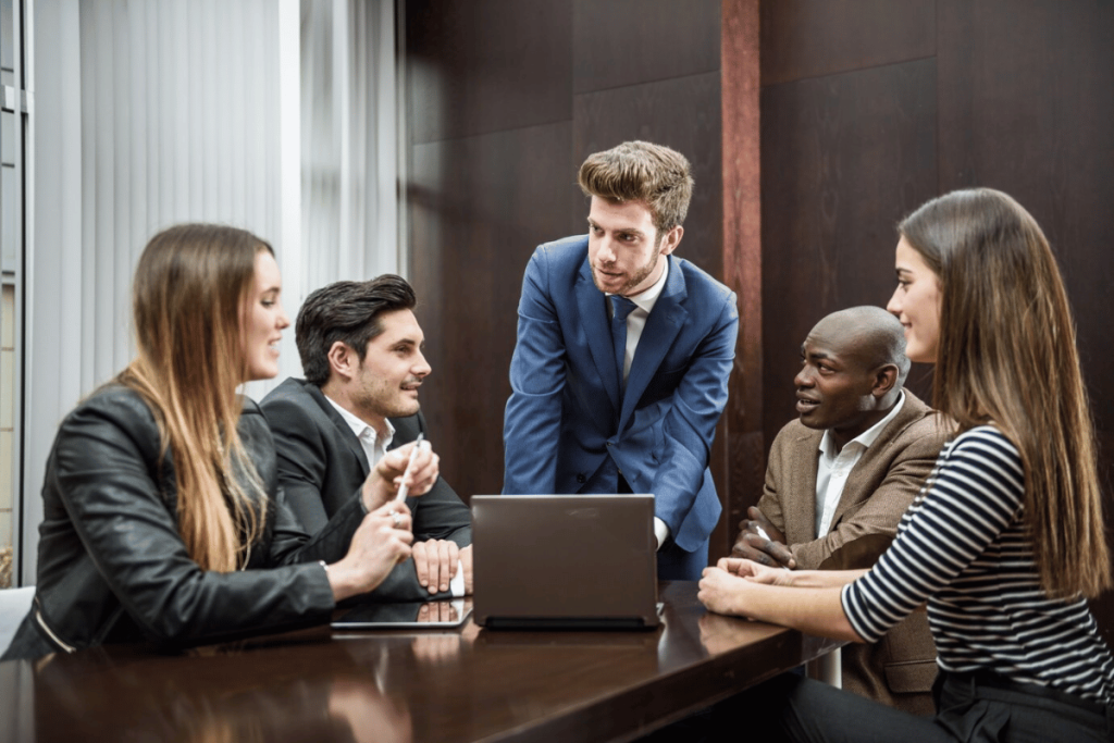 A group of business people sitting around a table with a laptop.
