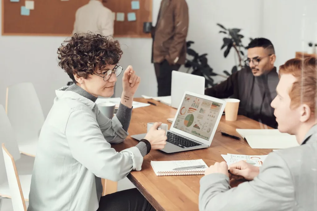 Team members engaged in a business meeting with data analysis on screen.