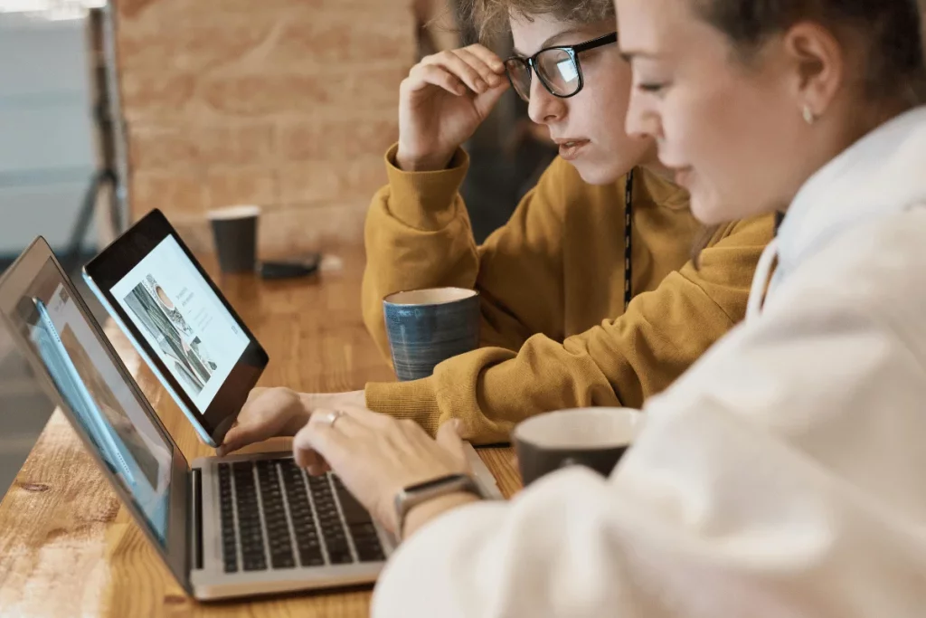 Two people working together on a project using a laptop and a tablet.