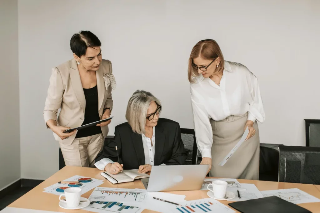 Female colleagues collaborating on a project, reviewing documents and a laptop.